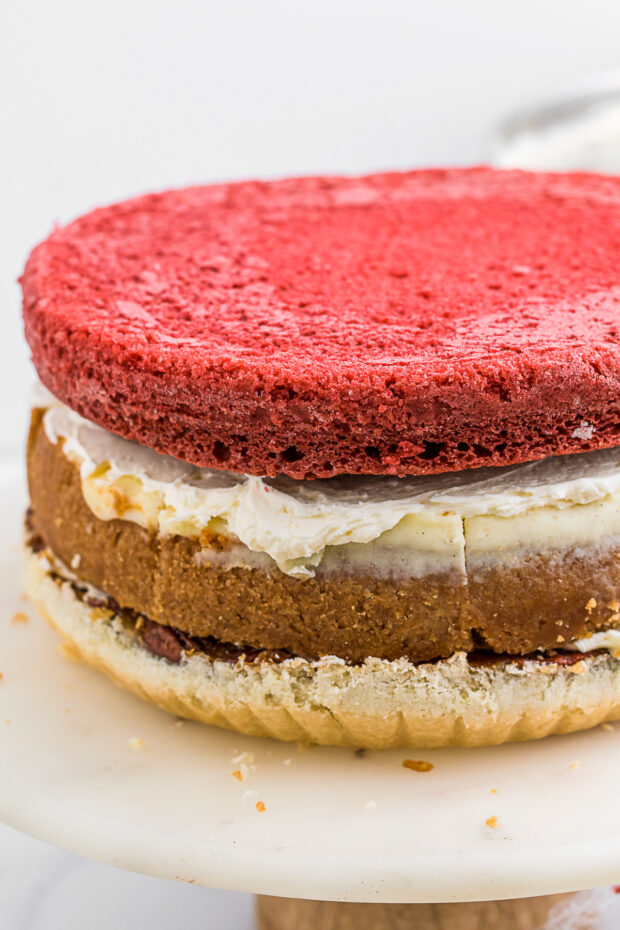 Red velvet cake sitting on top of a cheesecake and pecan pie. 