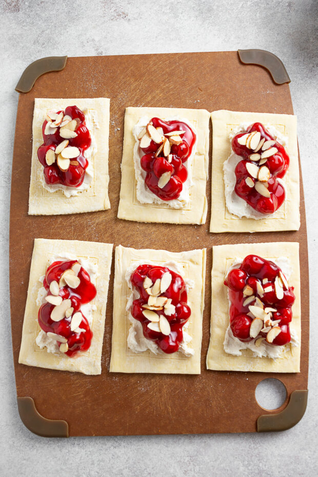 Uncooked Danish topped with cherries and almonds. 