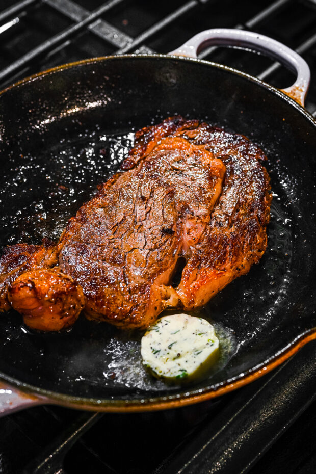 Ribeye steak cooking in a skillet. 