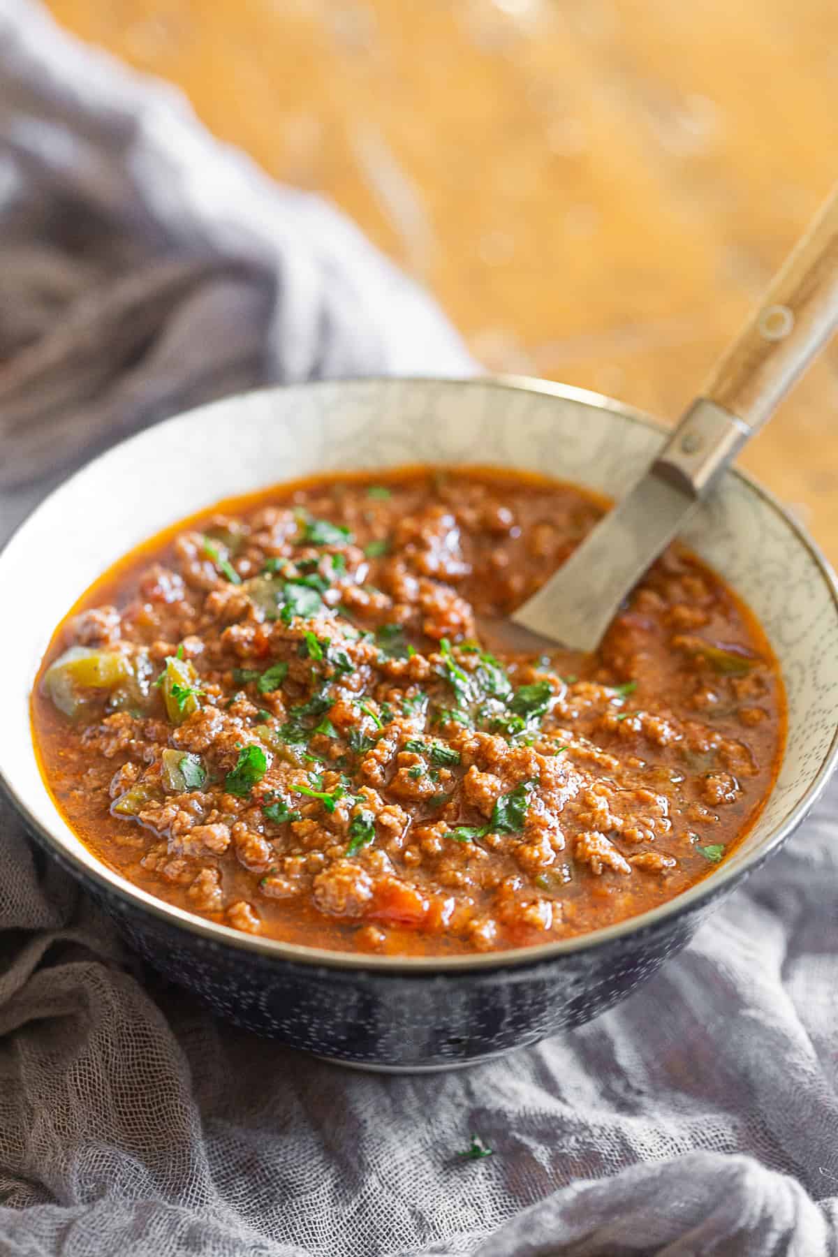 Ground Pork Chinese Chili in a bowl with a spoon. 
