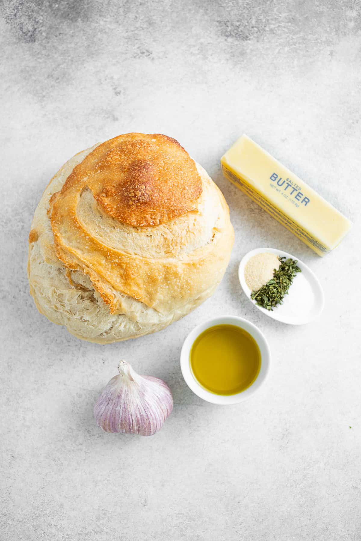sourdough bread, butter, olive oil, garlic and seasonings on a table. 