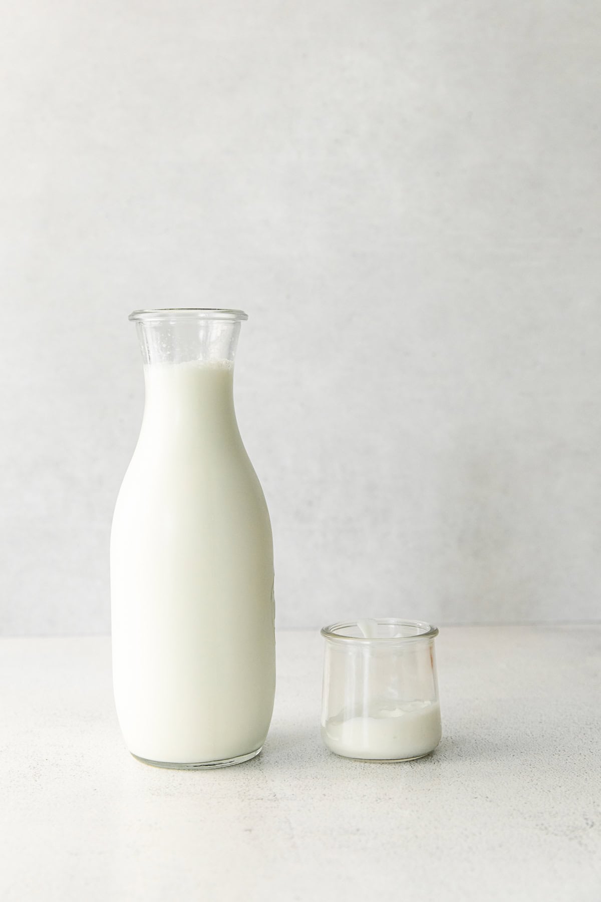 a bottle of milk and a cup of yogurt sitting on a table. 