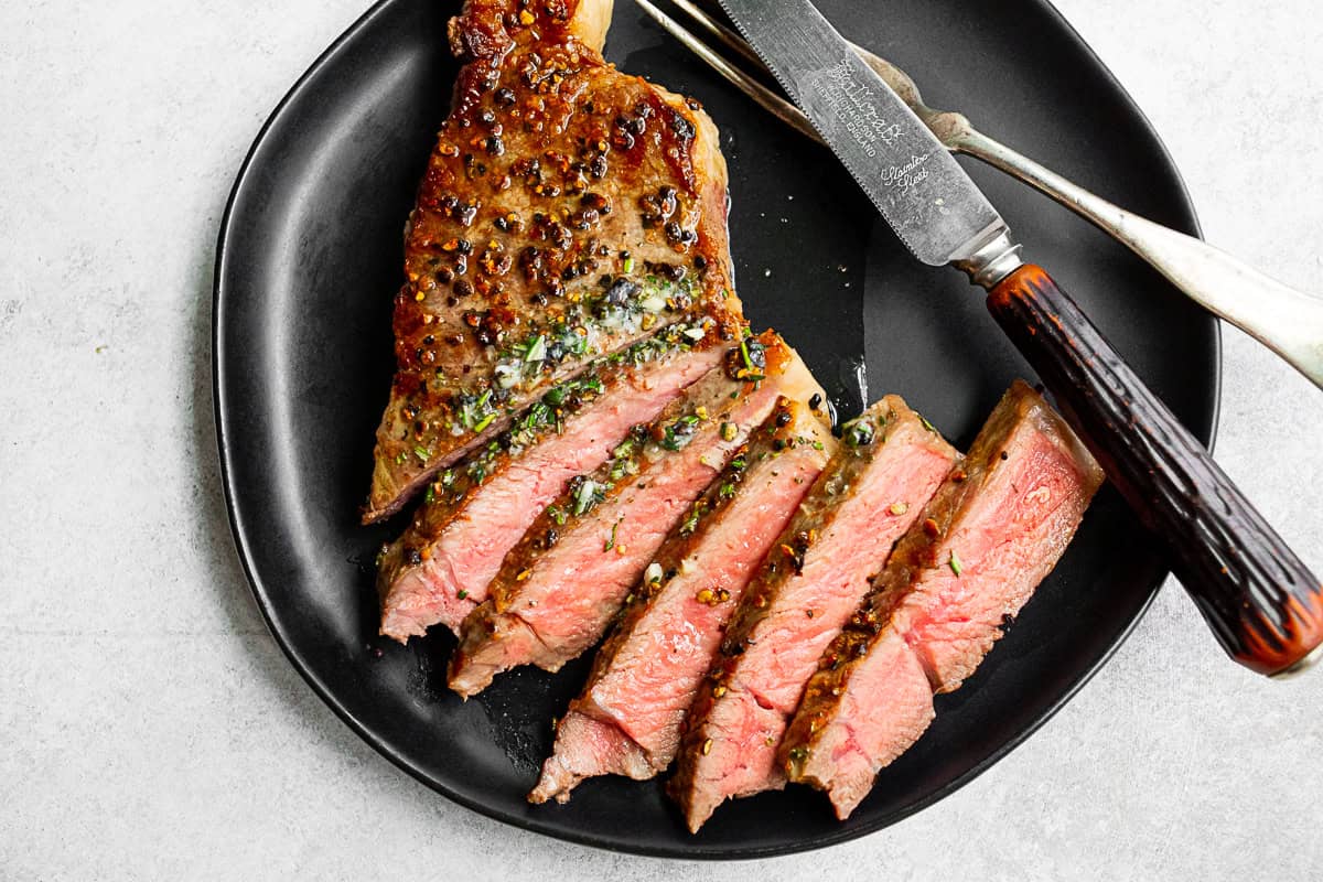 sliced cast iron seared strip steak steak on a black plate