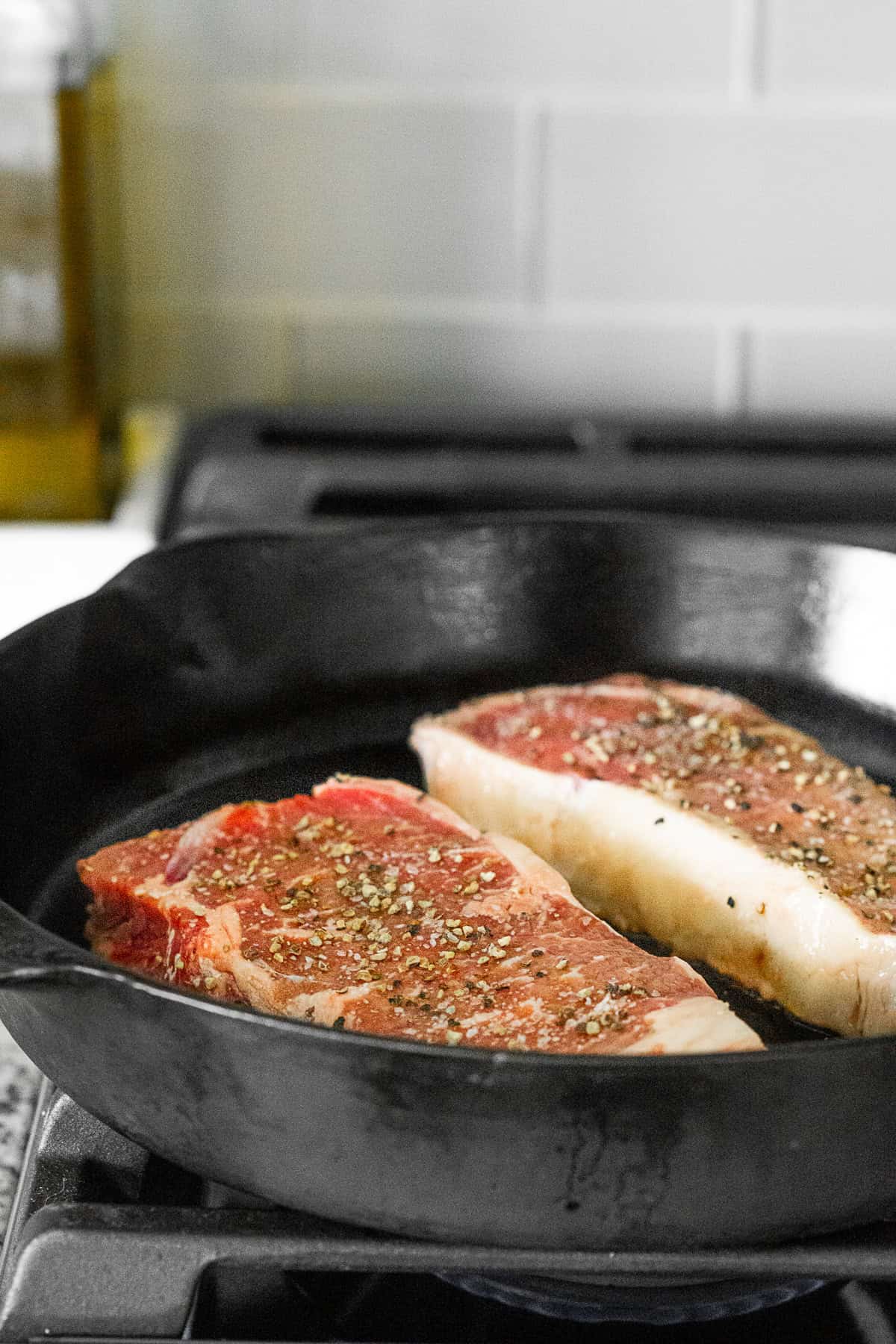 steaks cooking in a cast iron skillet on a stove
