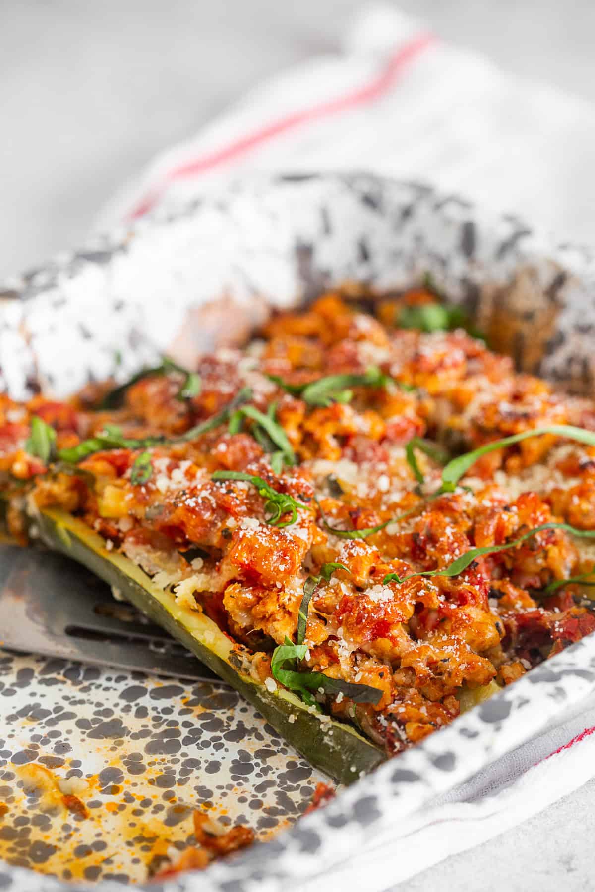 A spatula picking up a stuffed zucchini boat.