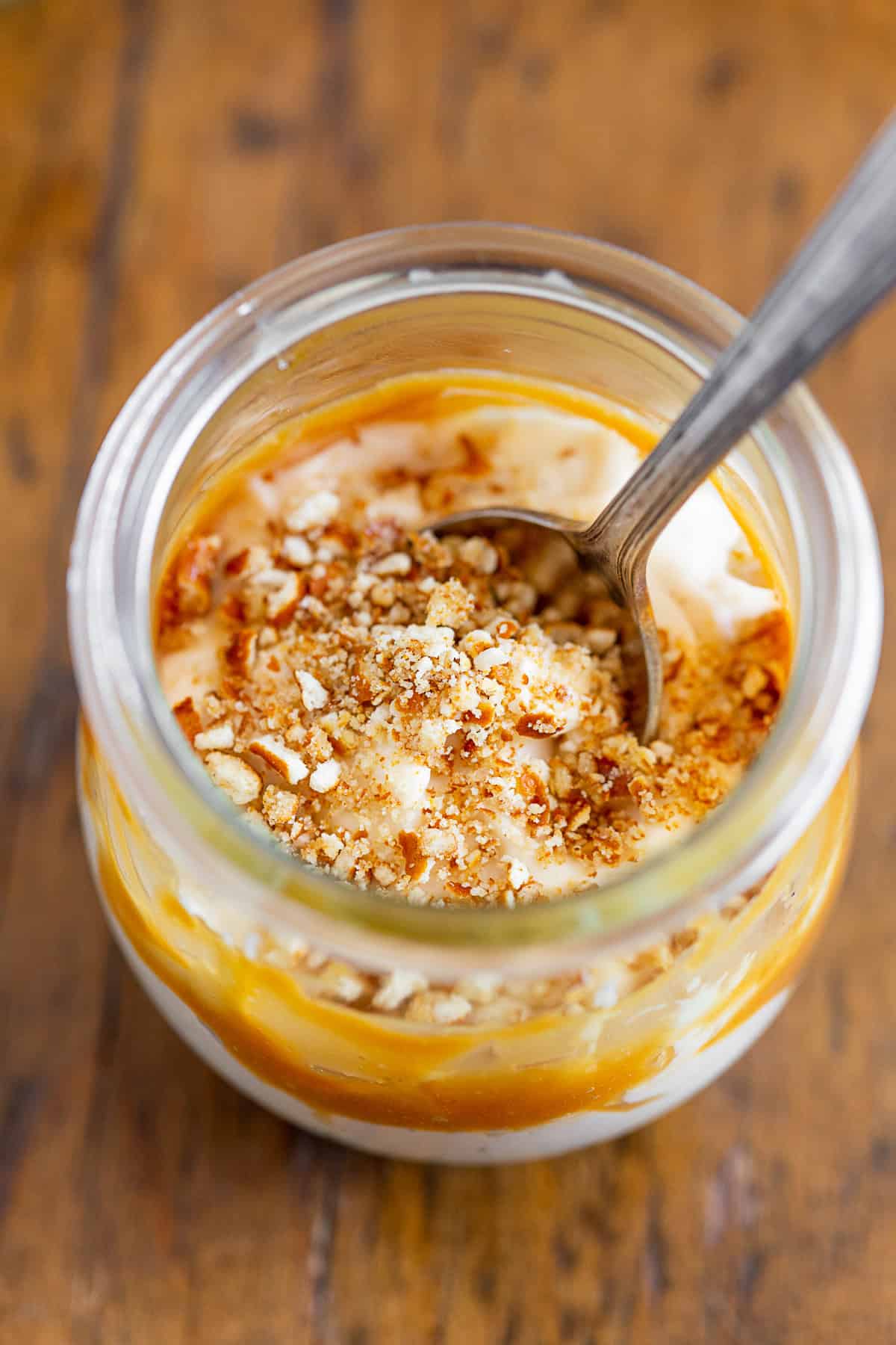 A spoon in a jar of No Bake Caramel Cheesecake.