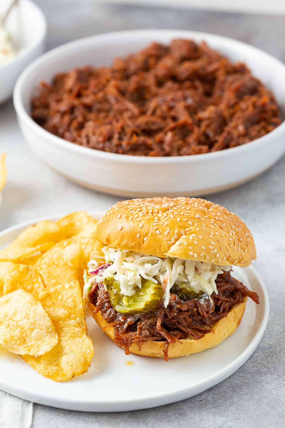 BBQ shredded beef on a bun with coleslaw and pickles. 