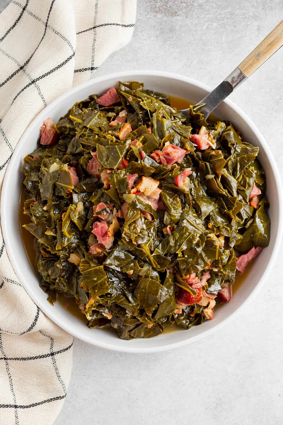 Instant Pot Collard Greens on a table with a wooden spoon and napkin.