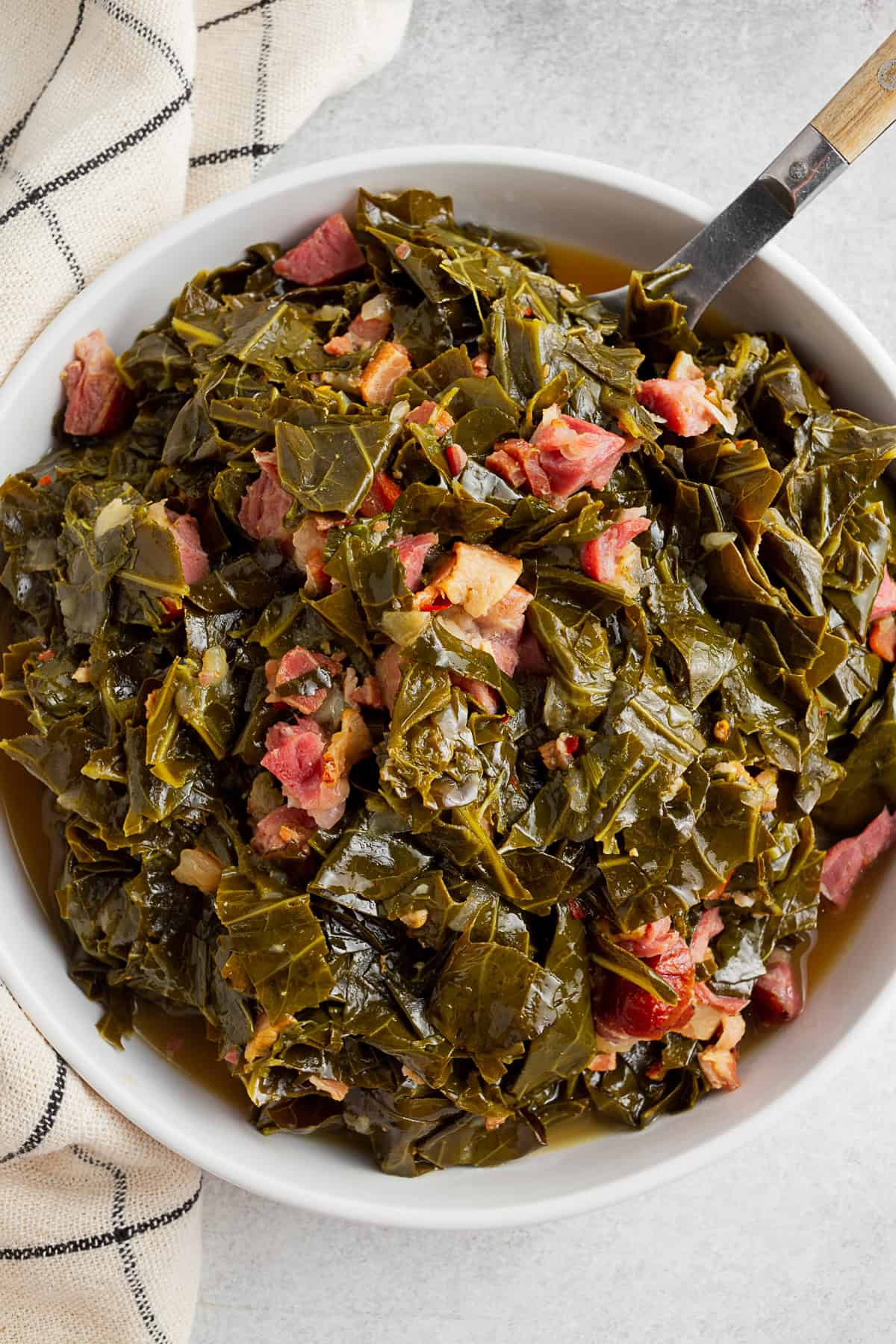 Instant Pot Collard Greens in a white bowl with a wooden spoon.