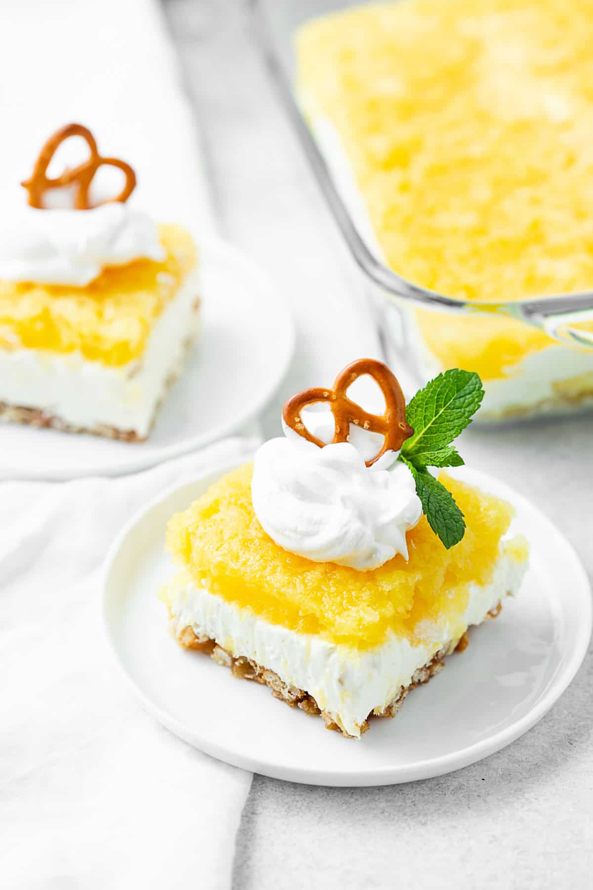 Pineapple Pretzel Salad sliced on a white plate. 