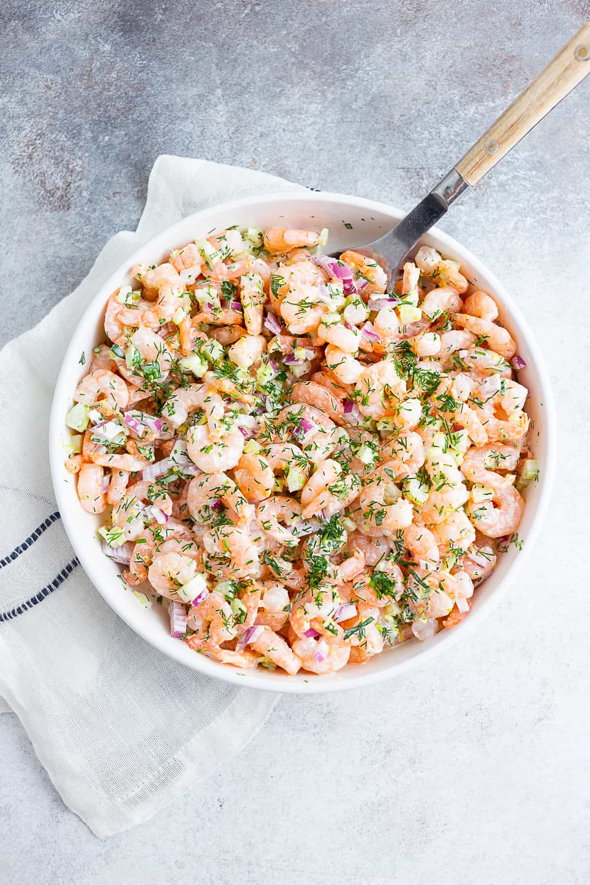 Classic Shrimp Salad in a large white bowl with a spoon.