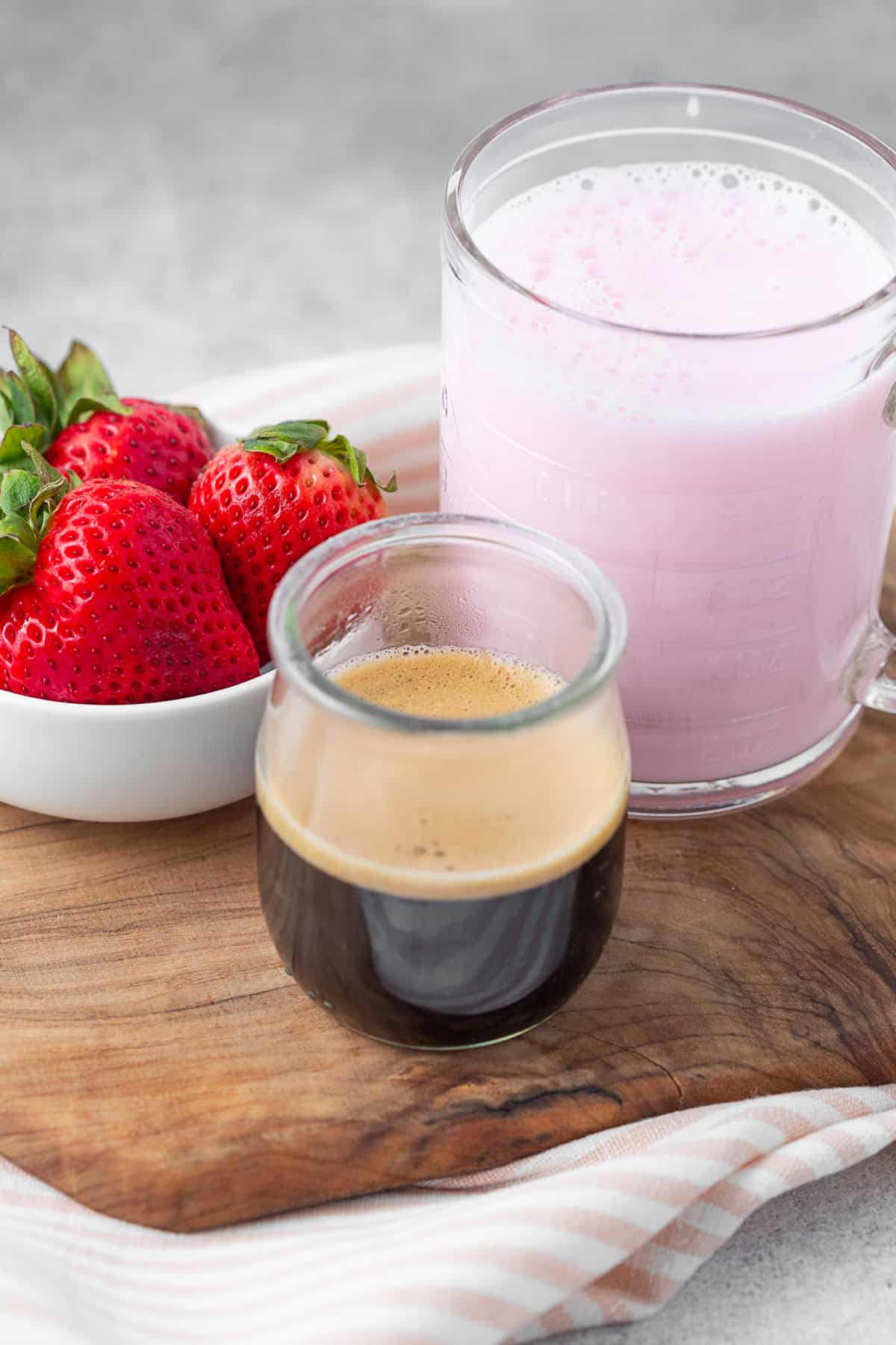 Strawberry milk, espresso and berries on a table.