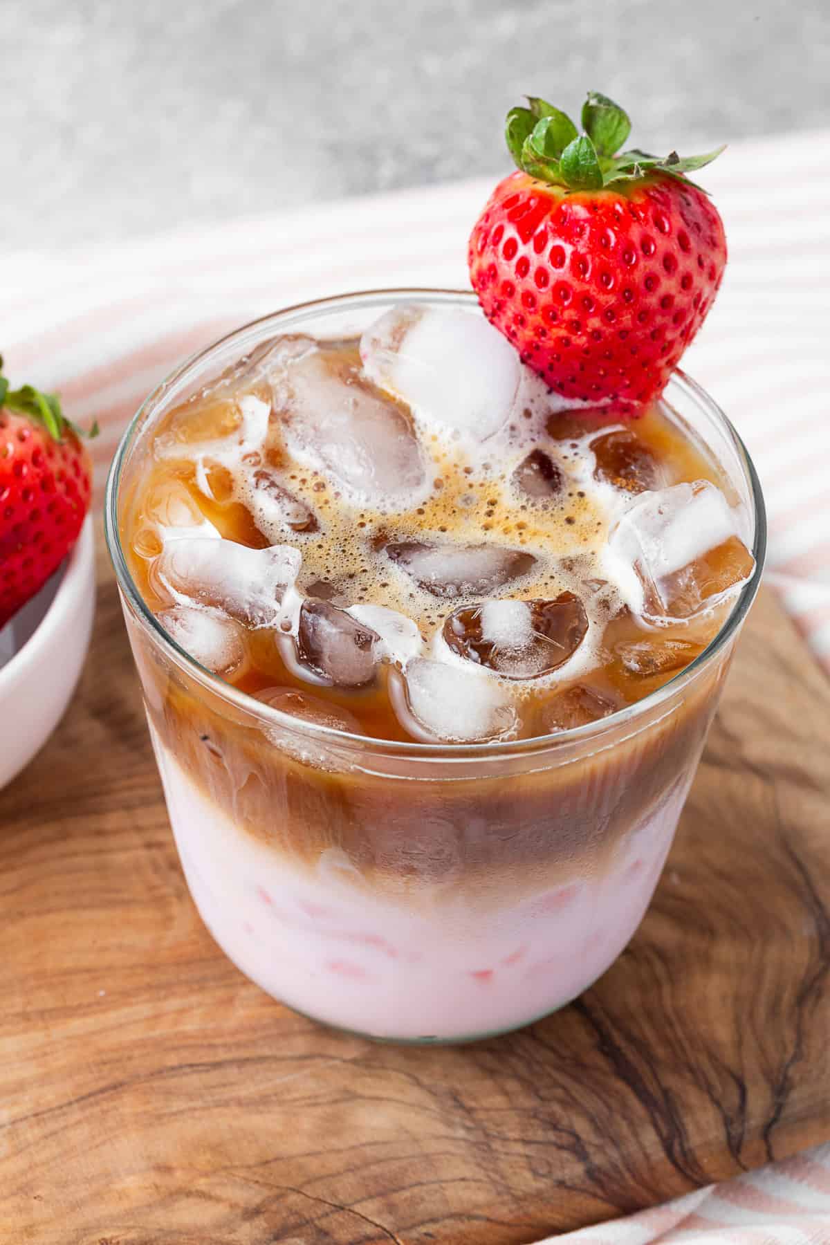 strawberry milk latte in a glass with a fresh strawberry.