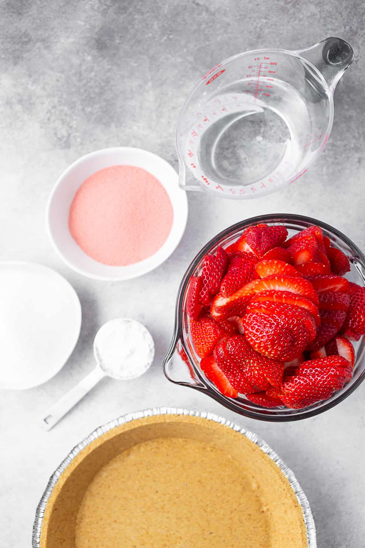 Fresh berries, crust, jello, sugar, and water on a table. 
