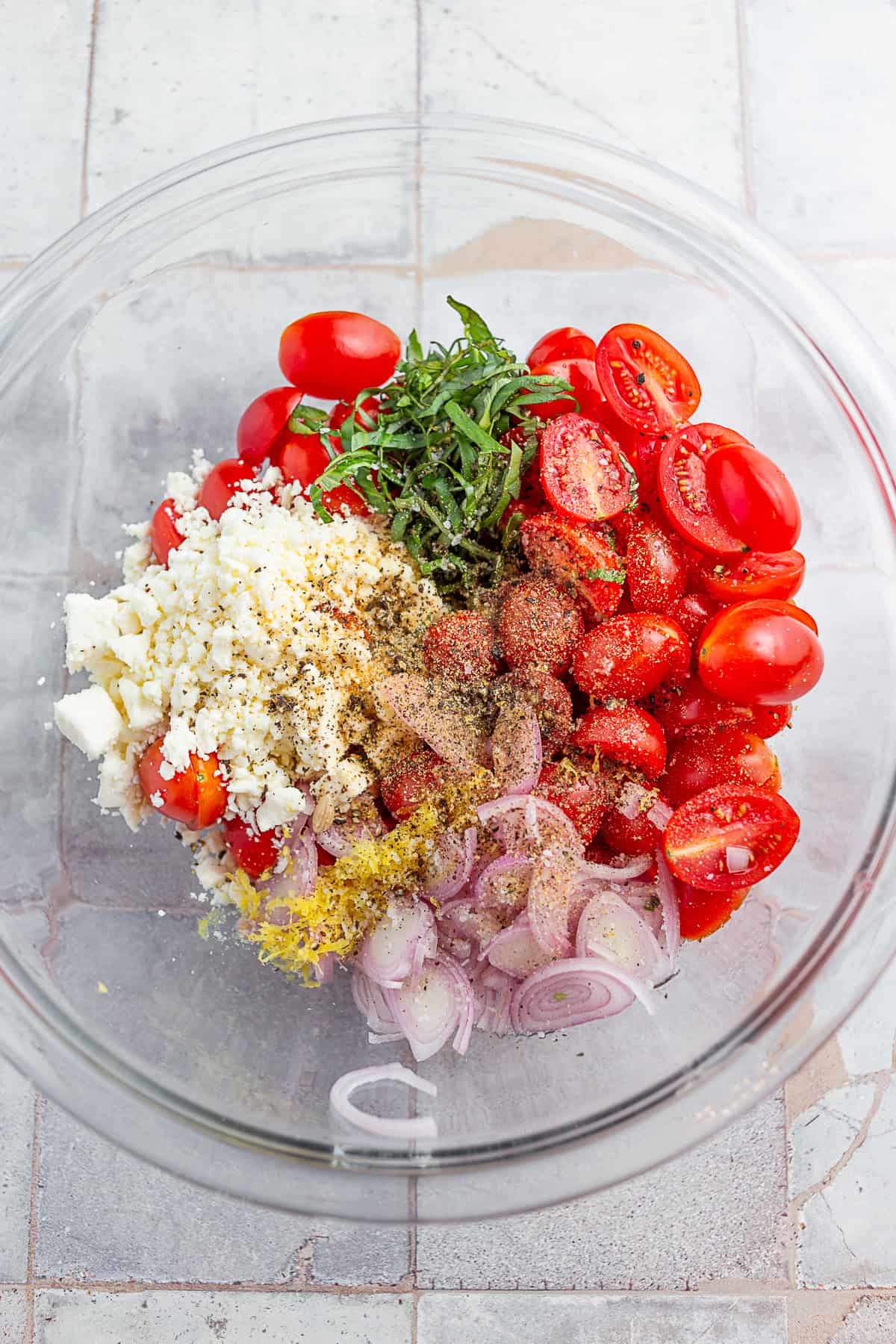 tomatoes, shallots, feta cheese, basil, lemon zest and spices in a bowl.
