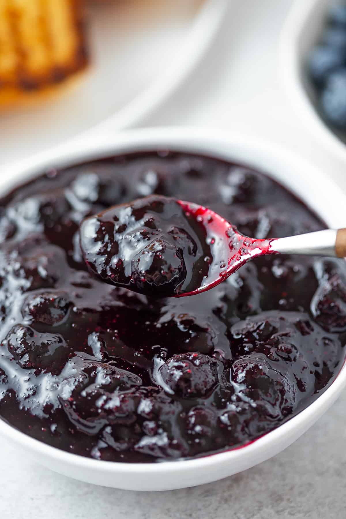 Blueberry Compote in a bowl with a spoon taking a spoonful.