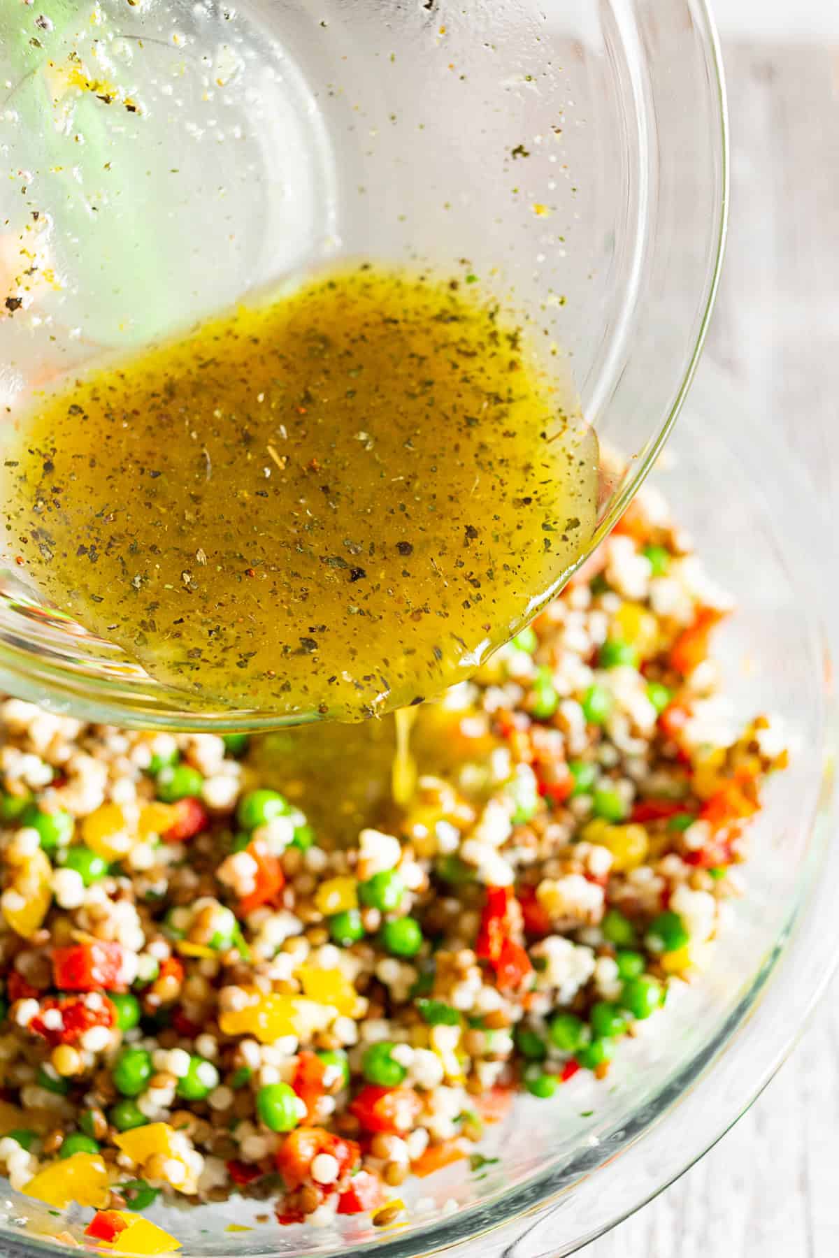 Vinaigrette being poured over lentil couscous salad.