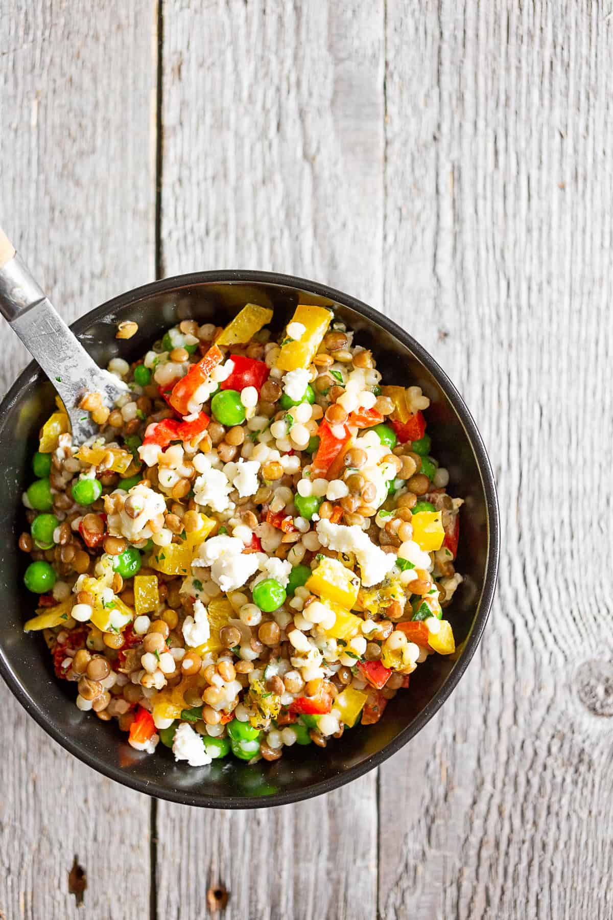 Bowl of lentil couscous salad with goat cheese on top.