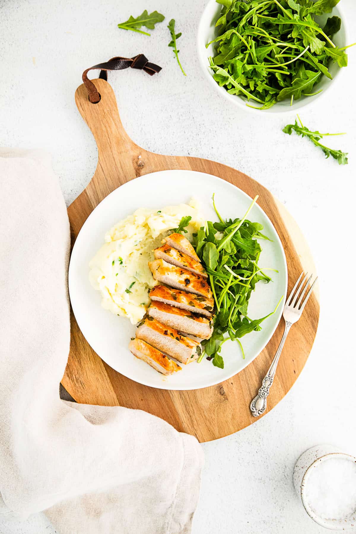 Grilled pork chops served on a white plate with a fork. 