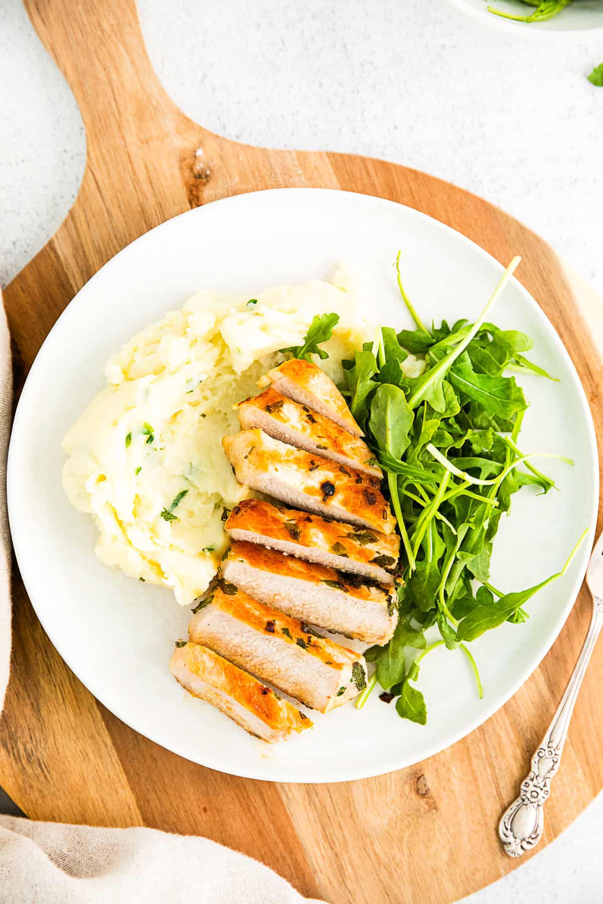 Herbed Marinated Grilled Pork Chop on a plate with mashed potatoes and salad. 