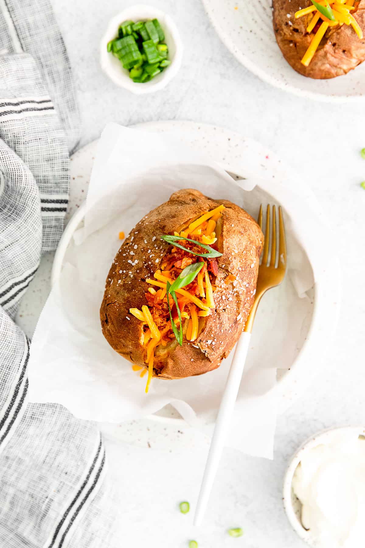 Air Fryer Baked Potatoes on a plate topped with cheese and bacon.