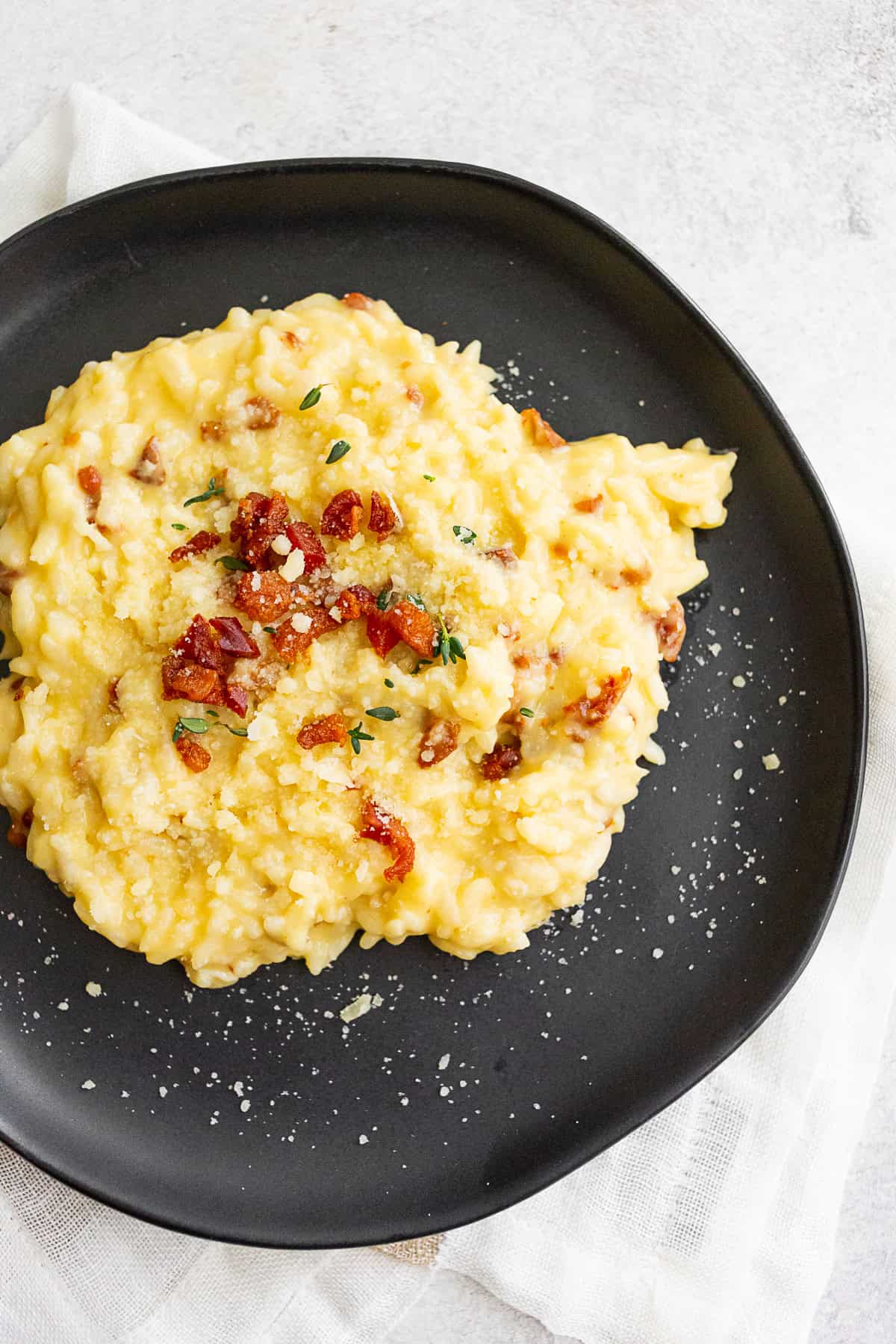 Instant Pot Risotto Carbonara on a black plate. 