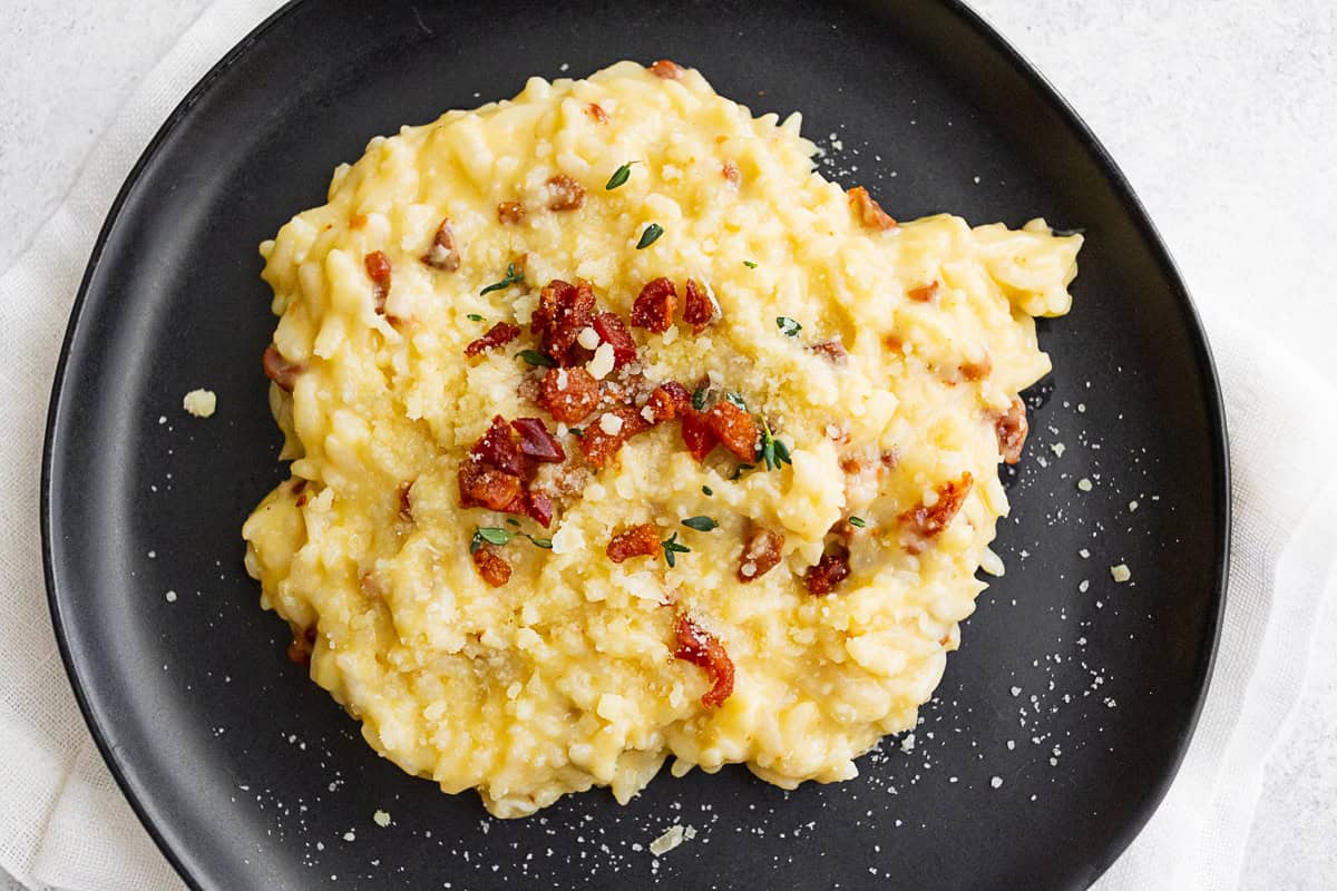 Instant Pot Risotto Carbonara sprinkled with cheese, bacon, and fresh thyme. 