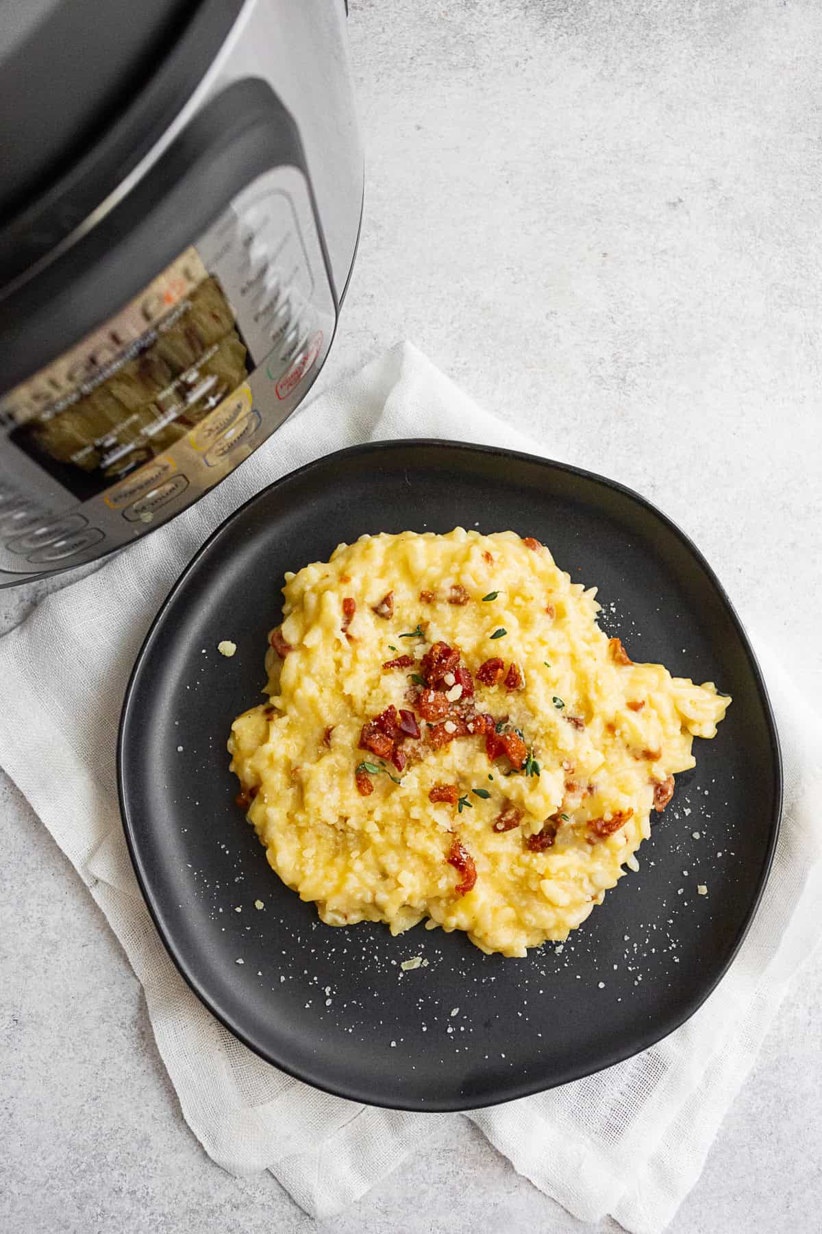 Instant Pot Risotto Carbonara on a plate with an instant pot sitting next to it. 