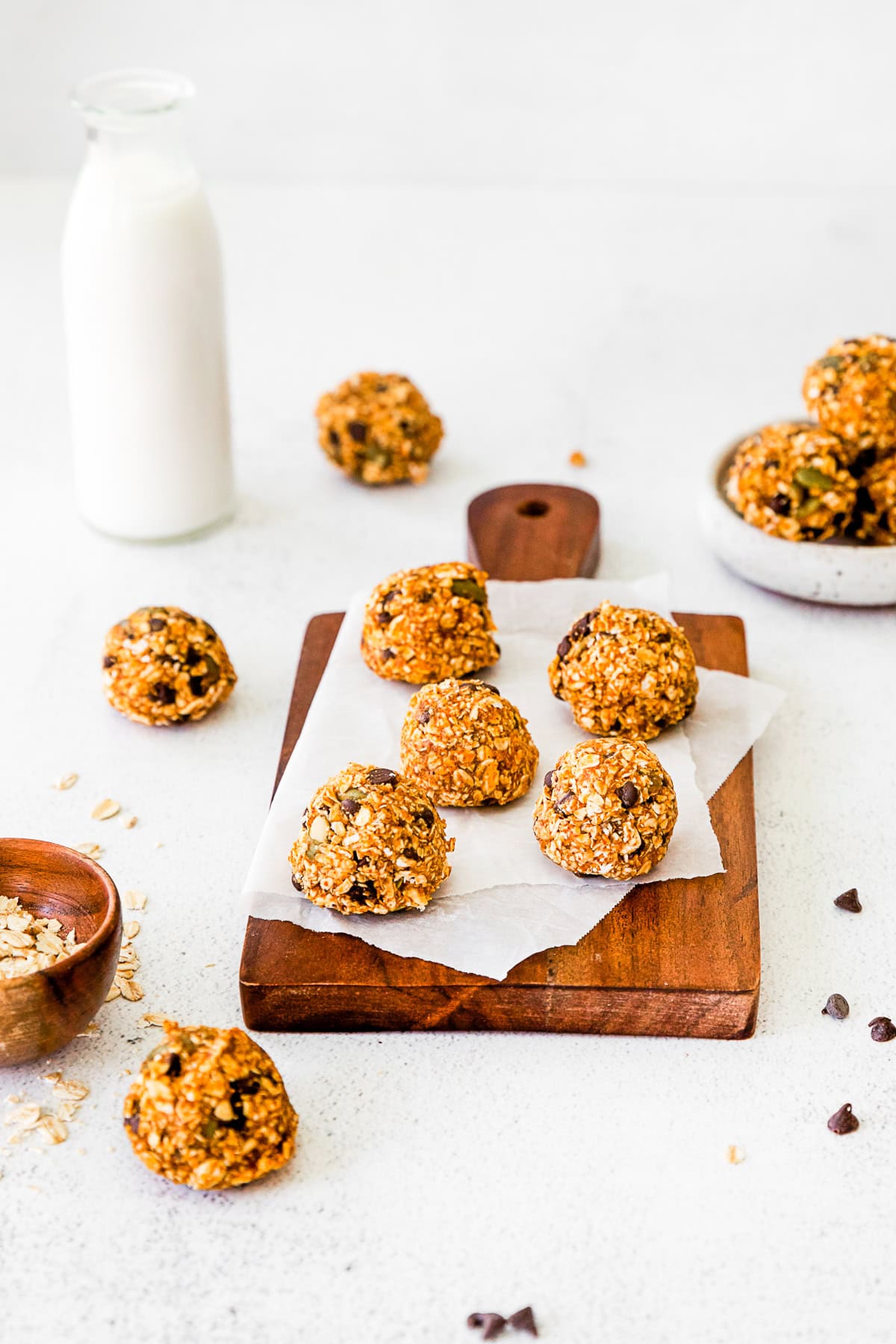 Pumpkin Energy Balls sitting on parchment paper on a wooden cutting board. 