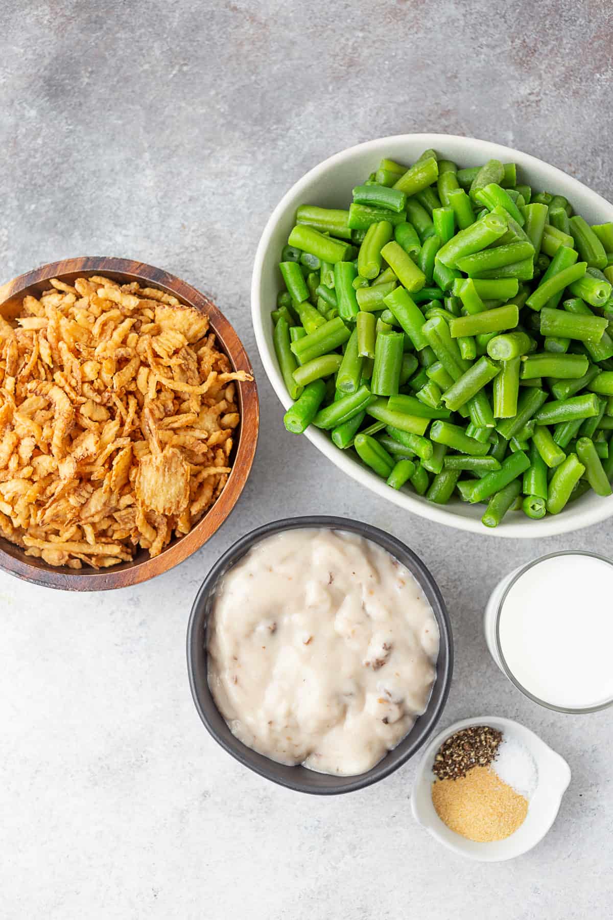 green beans, crispy fried onion, cream of mushroom soup, spices, and milk sitting on a table.