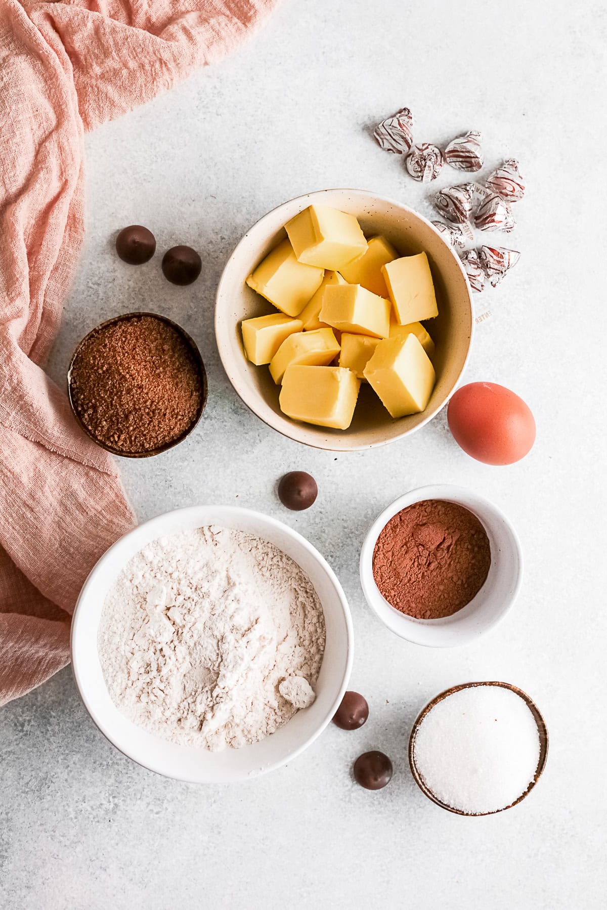 brown sugar, egg, butter, flour, granulated sugar, unsweetened cocoa powder, and kisses on a table. 