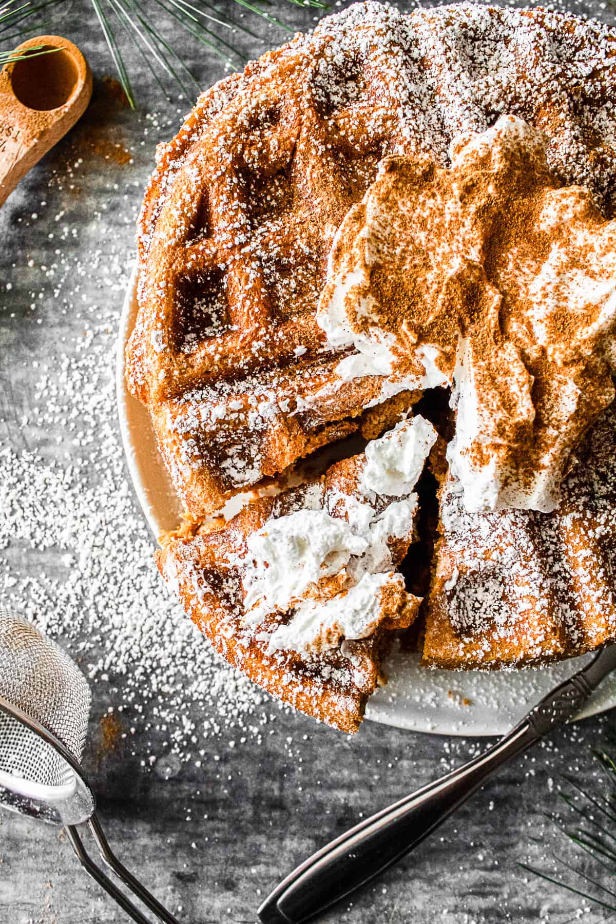 Gingerbread Waffles on a plate with powdered sugar and whipped cream. 