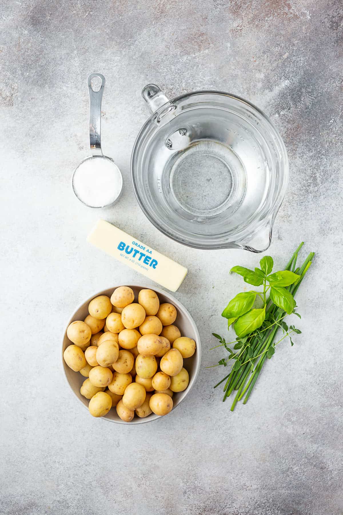 potatoes, water, herbs, butter, and salt on a table. 