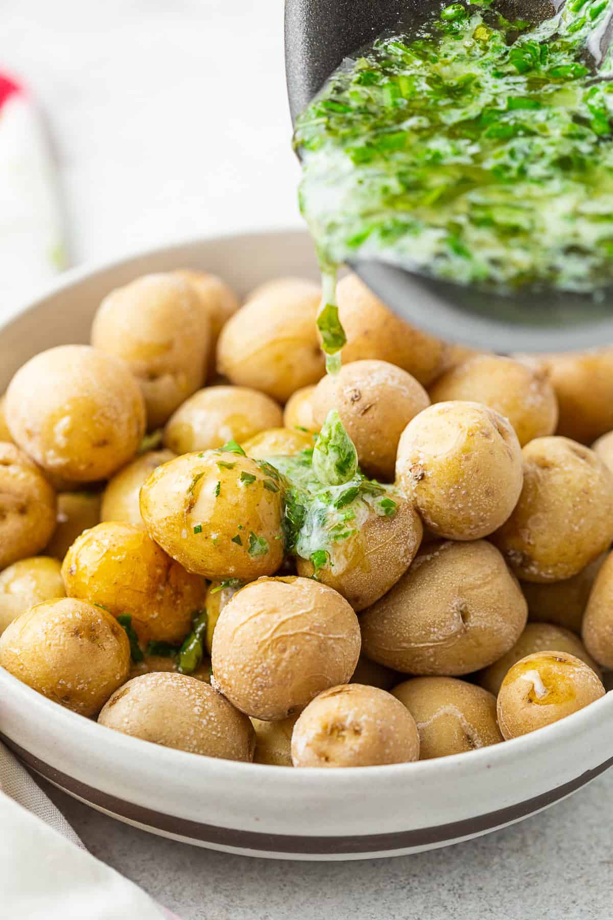 Pouring herb butter overtop salt potatoes. 