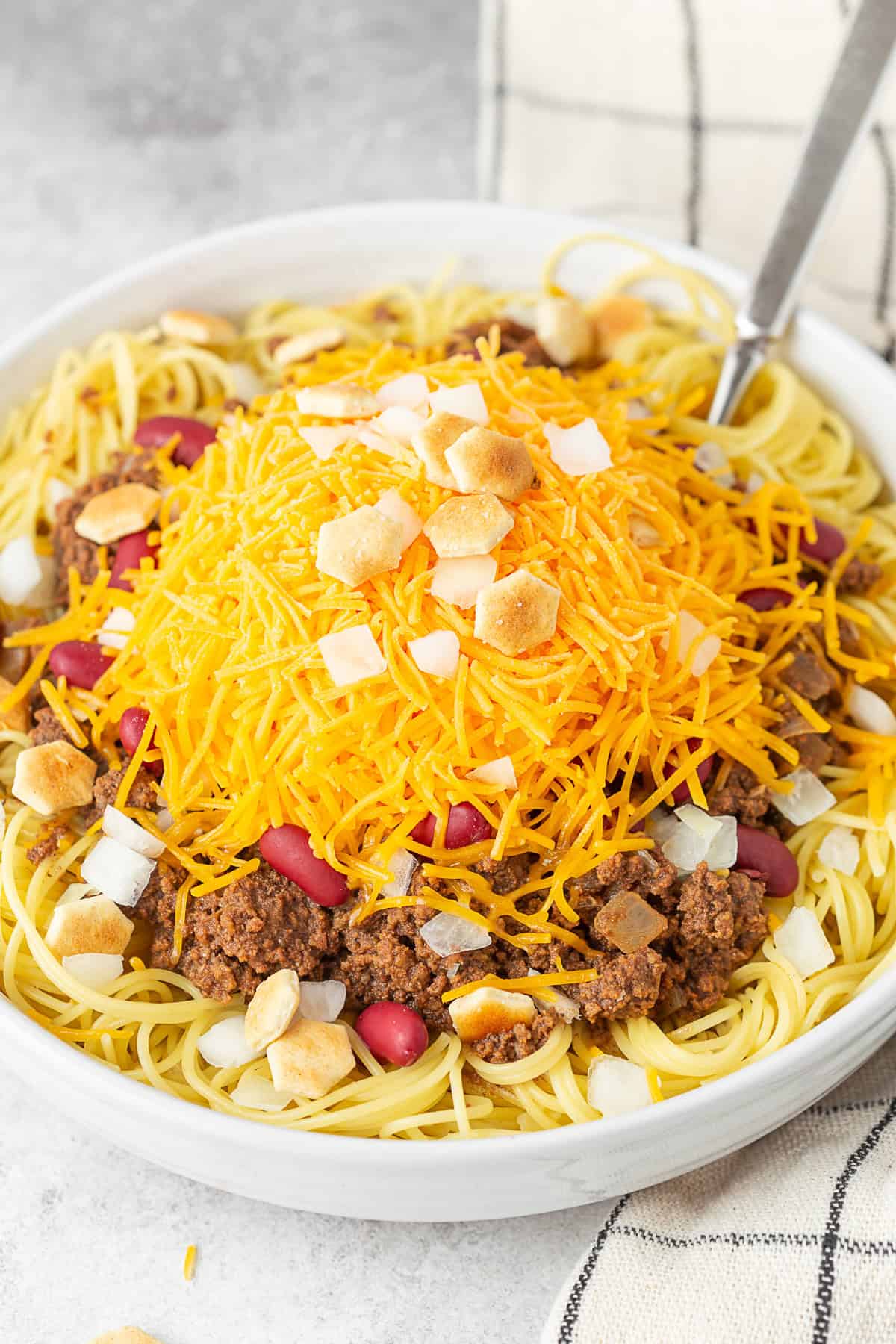 Cincinnati Chili topped with onion, beans, cheese, and oyster crackers. 